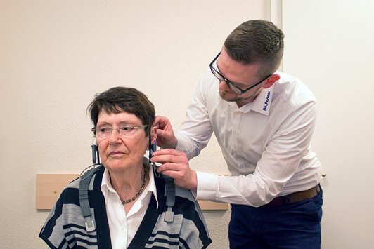 Hörtest bei älterer Frau durch Hörakustiker in moderner Hörakustik-Filiale.